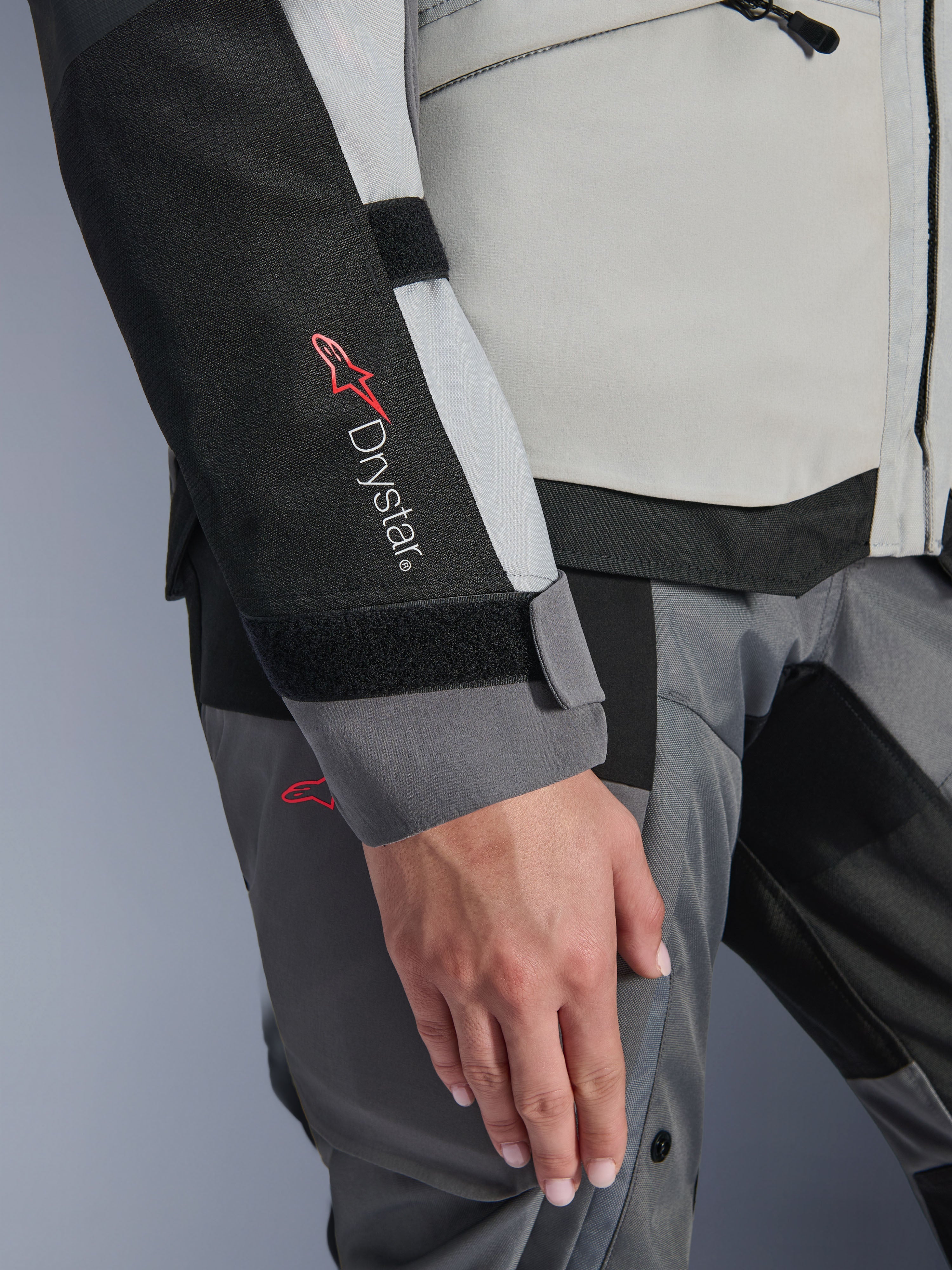 Alpinestars Stella Andes V4 Drystar®-jacka för dam, isgrå och mörkgrå, närbild med Drystar®-logotypen på den svarta ärmpanelen, justerbar kardborrestängning vid handleden och slitstark textilkonstruktion för adventure touring