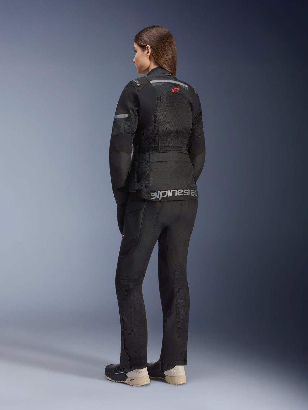 Alpinestars Stella Andes Air Drystar®-jacka, motorcykeljacka för dam, svart, sedd bakifrån buren med matchande körbyxor och stövlar, med stora ventilationspaneler i mesh, en röd stjärnlogotyp och silverfärgad Alpinestars-logotyp på nedre delen av ryggen.