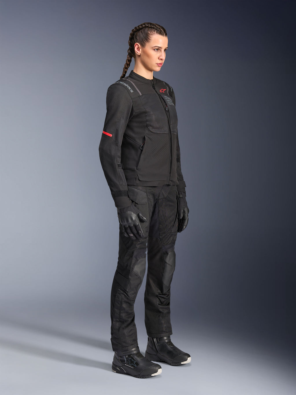 Kvinnlig förare iklädd Alpinestars Stella Andes Air Drystar®-byxor i svart, adventure-textilbyxor med ventilationspaneler i mesh, stylad med matchande Stella-jacka, handskar och stövlar för en komplett touring-outfit för motorcykel.
