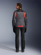 Ryggvy av en modell som bär Alpinestars Stella St-2 Air-jacka för dam i Deep Gray och Dark Gray med Fluo Coral-detaljer, med stora ventilationspaneler i mesh på ryggen och reflekterande logotypdetaljer, matchad med svarta motorcykelbyxor och handskar.