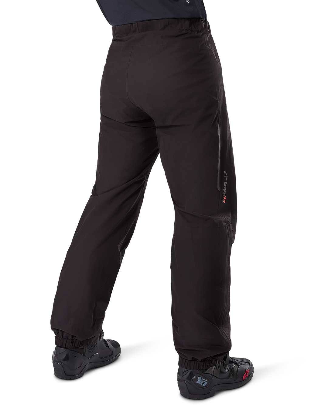 Alpinestars Amt-8 Stretch Drystar® XF byxfoder, svart, vy bakifrån som visar det vattentäta fodret buret över svarta motorcykelstövlar, med Drystar XF-logotyp på underbenet, elastiska benslut och lätt stretchmaterial för adventure touring.