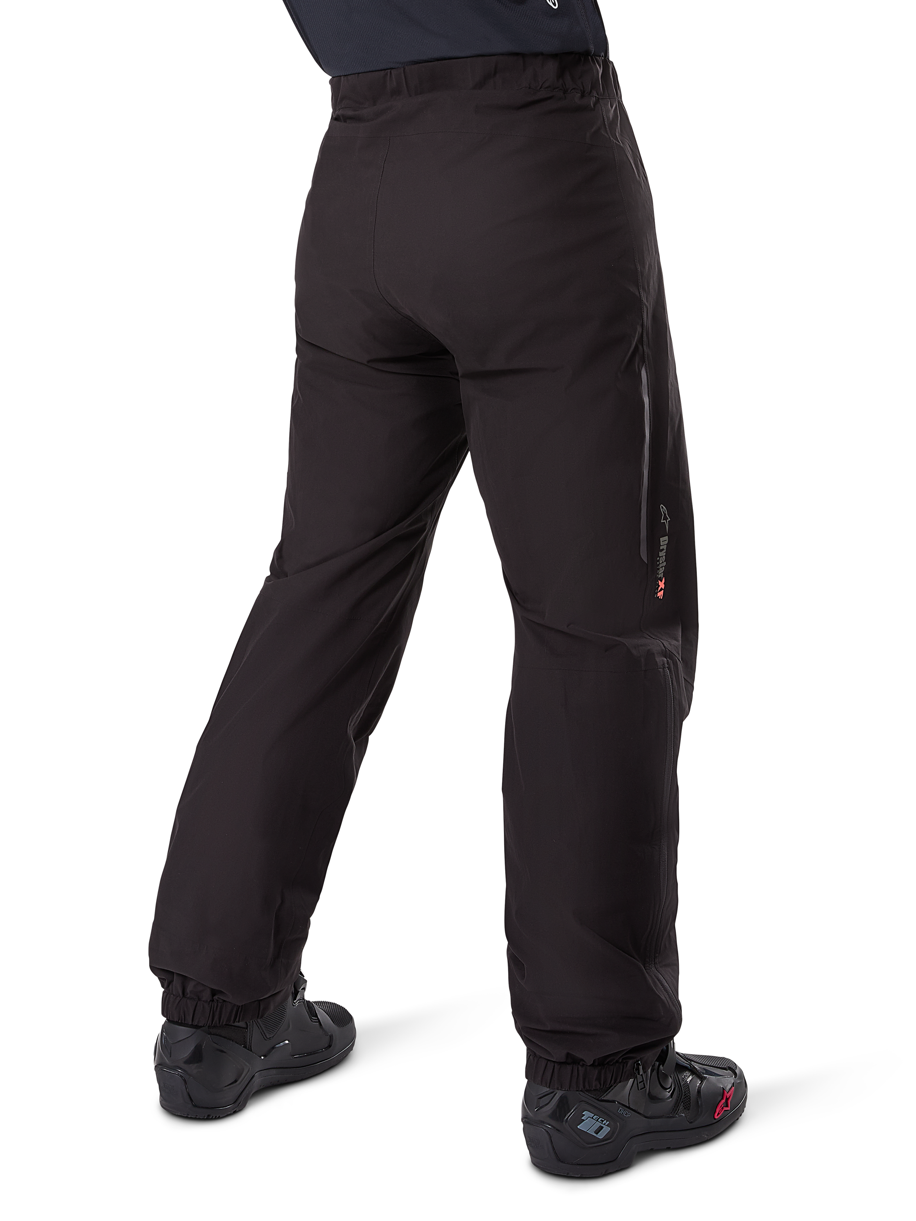 Alpinestars Amt-8 Stretch Drystar® XF byxfoder, svart, vy bakifrån som visar det vattentäta fodret buret över svarta motorcykelstövlar, med Drystar XF-logotyp på underbenet, elastiska benslut och lätt stretchmaterial för adventure touring.