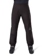 Alpinestars AMT-8 Stretch Drystar® XF byxfoder, svart, sedd framifrån buren med svarta motorcykelstövlar, med grå stjärnlogotyp och AMT-märkning på benet, mångsidiga vattentäta och vindtäta motorcykelkläder