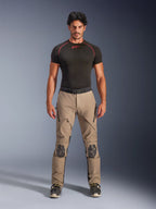 Manlig modell i Alpinestars AMT-8 Stretch Drystar® XF byxor i Walnut och Black, kombinerat med ett svart kortärmat baslager, äventyrsbyxor för touring med förstärkta knän, dragkedjeförsedd ventilation och ergonomisk stretchdesign.