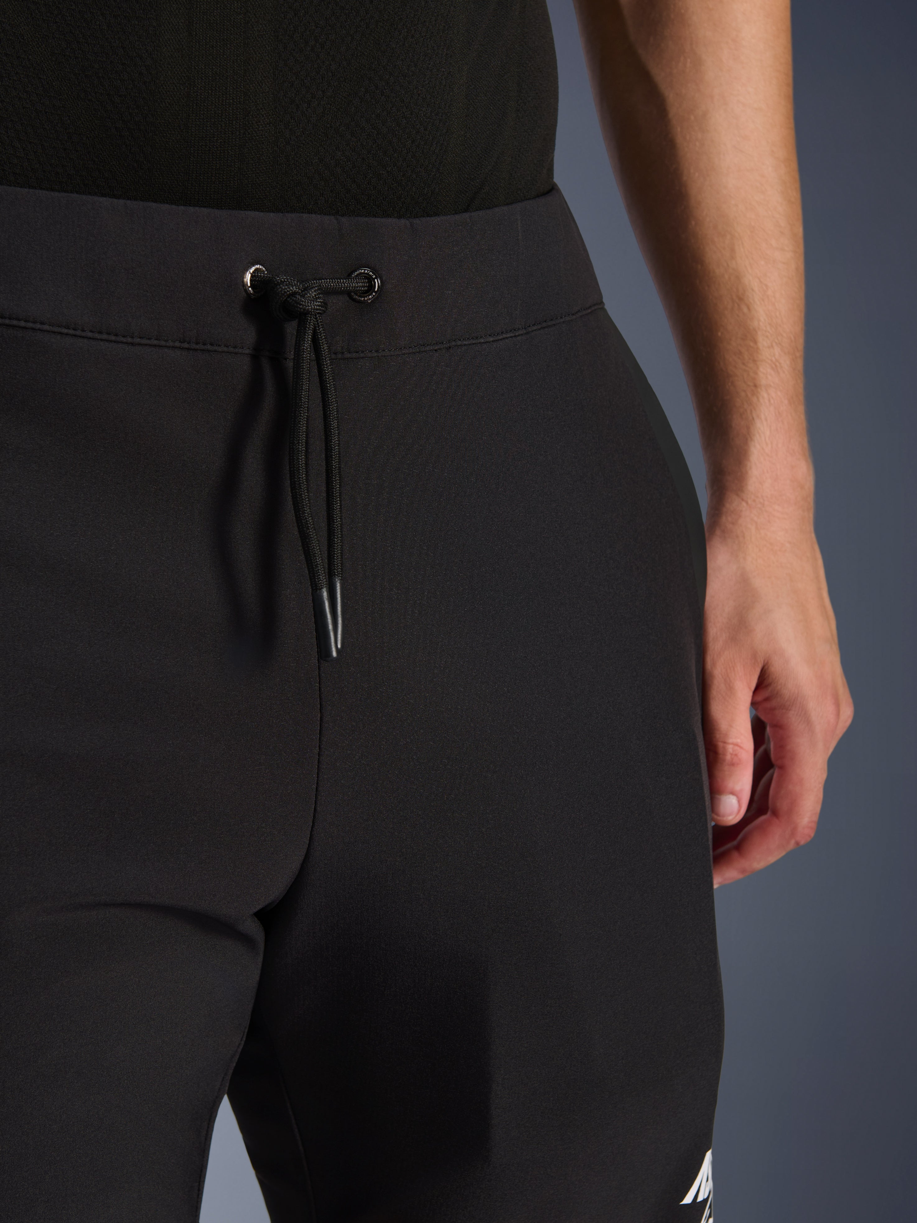 Alpinestars Aeroshell Pants, Black softshell motorcycle pants, close-up view of the elastic waist and drawstring cordon closure, modern minimalist design, durable textile construction for casual touring