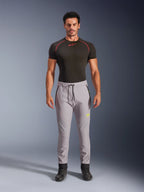 Manlig modell i Alpinestars Aeroshell-byxor i Mid Gray och Yellow Fluo, crossover sportiga softshellbyxor med elastisk midja med dragsko och fickor med dragkedja, kombinerat med en svart kortärmad funktionströja, modern atletisk design för landsvägs- och vardagskörning