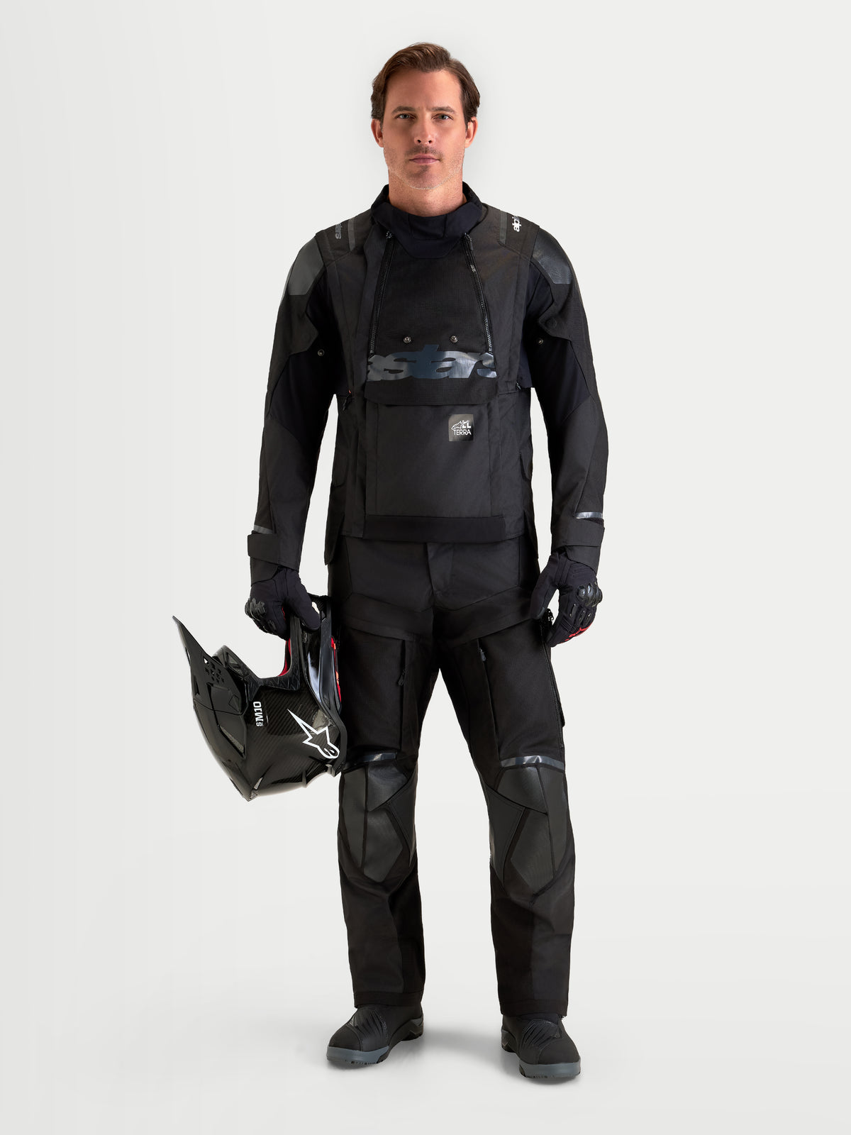 Alpinestars Harok V2 Drystar byxor, svarta äventyrs-motorcykelbyxor för herr, frontvy på modell som håller en hjälm