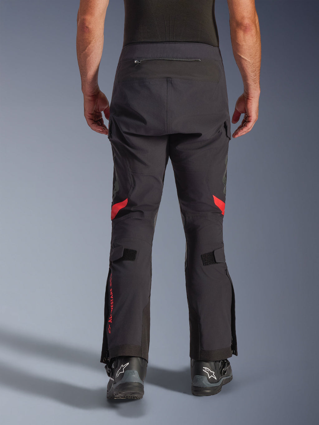 Alpinestars Halo Pro Drystar® XF Laminerade Byxor, Black Dark Shadow, vy bakifrån av äventyrsmotorcykelbyxor med röda detaljer bakom knäna och röd logotyp på vaden, bärs med svarta Alpinestars-stövlar, slitstarkt 3L-laminerat textilmaterial för prestanda i alla terränger