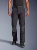 Alpinestars Halo Pro Drystar® XF Laminated Pants i Black Dark Shadow, äventyrsmotorcykelbyxor, frontvy på modell med magnetiskt midjespänne, ventilationsöppningar med dragkedja på låren och förstärkta knäpartier i läder, matchade med svarta MC-stövlar.