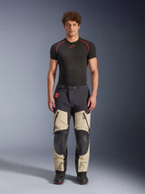 Alpinestars Halo Pro Drystar® XF Laminated Pants, Mastic Black, adventure motorcycle pants worn by a model with a black base layer and boots, featuring beige thigh panels with large zippered vents, black reinforced knee sections, and a magnetic buckle belt.