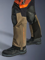Alpinestars Halo Pro Drystar® XF laminerade byxor, äventyrsbyxor för motorcykel, Walnut Rust och svart, närbild med förstärkta knäpaneler och orange logotyp, bärs med svarta touringstövlar, slitstark textilkonstruktion för terrängkörning