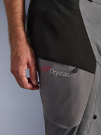Alpinestars Andes V4 Drystar® byxor, Black Dark Gray, närbild på lårdetalj med röd stjärnlogotyp och Drystar®-märkning, hållbar textilkonstruktion med dragkedjeficka, äventyrskläder för motorcykel