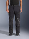 Alpinestars Andes Pro Drystar® XF byxor, svart mörkgrå adventure touring-motorcykelbyxor, framifrån, med 3-lagers laminerad konstruktion, integrerade knäskyddspaneler, vattentäta fickor med dragkedja och magnetiskt midjespänne, stylade med svarta MC-stövlar.