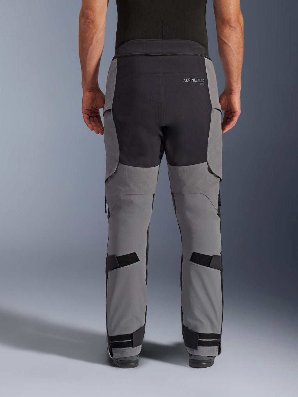 Alpinestars Andes Pro Drystar® XF byxor, motorcykelbyxor för äventyrskörning, mörkgrå och svarta, vy bakifrån som framhäver svart sätespanel med logotyp, justerbara remmar vid vaderna och anklarna, robust teknisk design för äventyrskörning