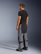 Alpinestars Andes Pro Drystar® XF byxor, äventyrsmotorcykelbyxor, mörkgrå och svarta, trekvartsvy bakifrån på modell, teknisk textilkonstruktion med svarta förstärkta paneler på sätet och insidan av benen, bärs med en svart baslager-t-shirt.