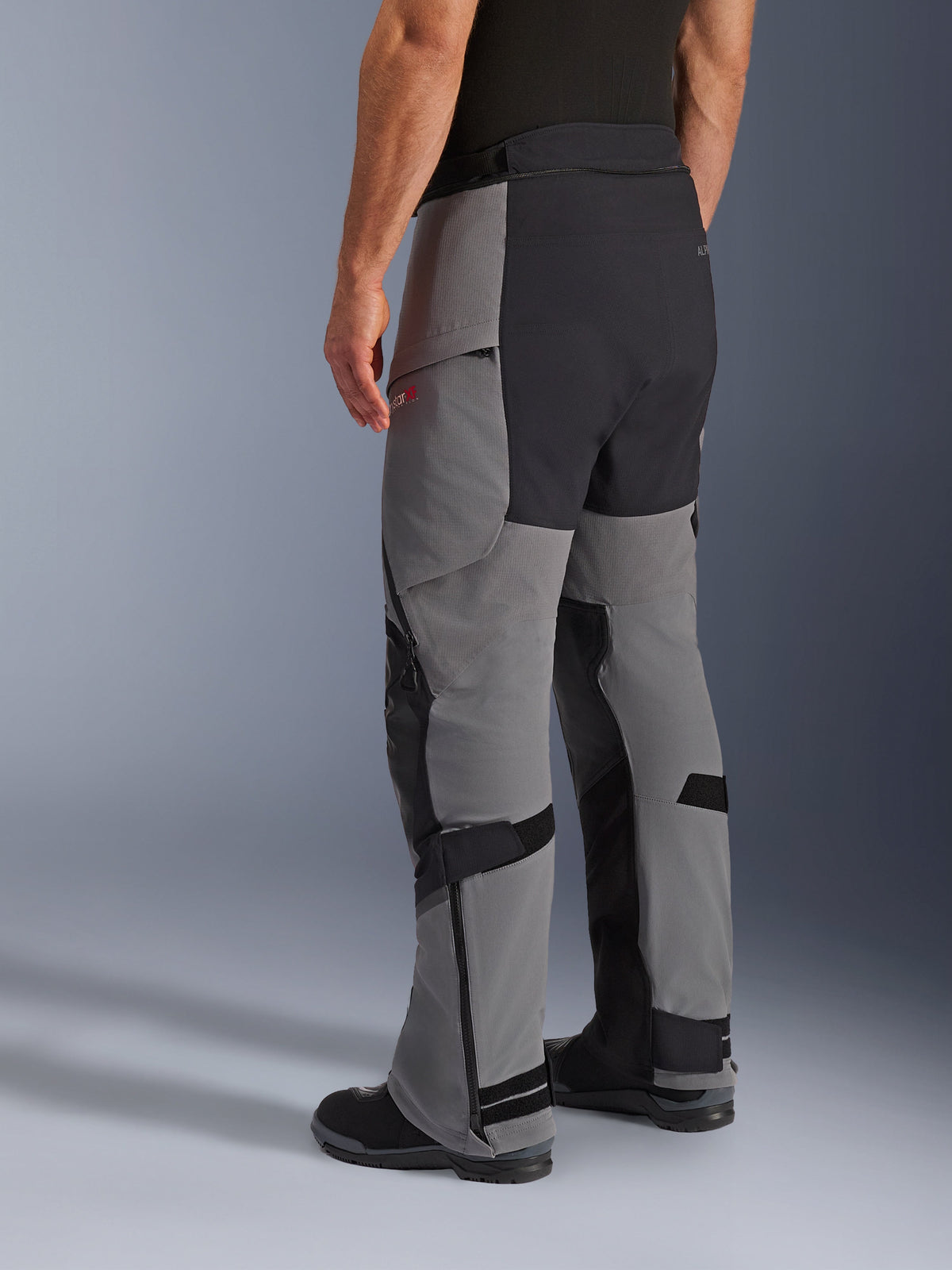 Alpinestars Andes Pro Drystar® XF byxor, äventyrsmotorcykelbyxor, mörkgrå och svarta, trekvartsvy bakifrån, textilkonstruktion med svart förstärkt säte och paneler på innerbenen, dragkedjor vid bensluten och justerbara flikar