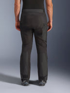 Alpinestars Cusco Drystar® byxor, MC-byxor, svarta, sedda bakifrån burna av en förare, med texturerade textilpaneler, ventilationsöppningar med dragkedja på låren och justerbara benslut, kombinerade med svarta Alpinestars-stövlar.