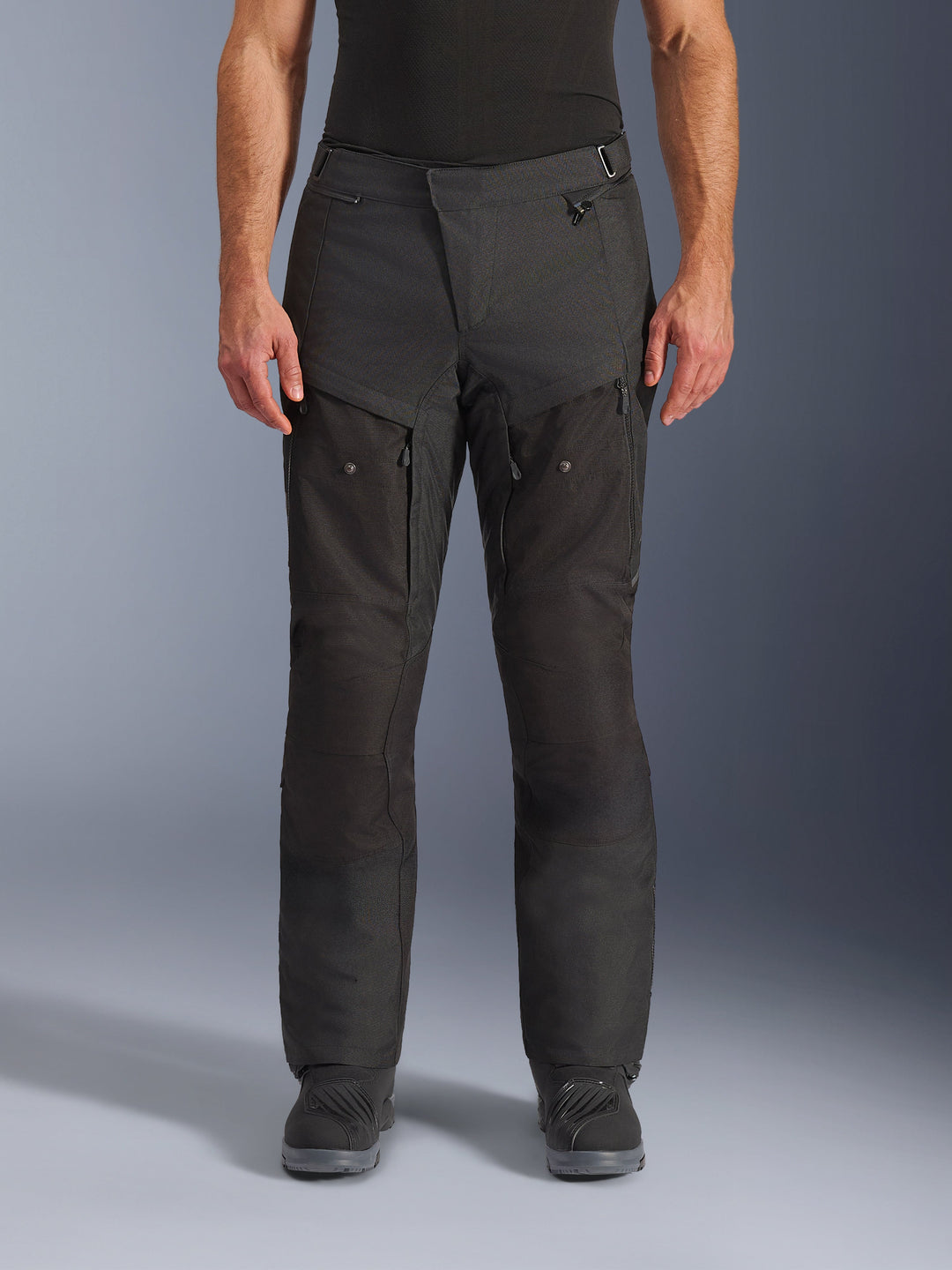 Alpinestars Cusco Drystar® byxor, adventure-motorcykelbyxor, svarta, vy framifrån med lårventilation med dragkedja och justerbar midja, slitstark ripstop- och 600D-textilkonstruktion, bärs med svarta stövlar