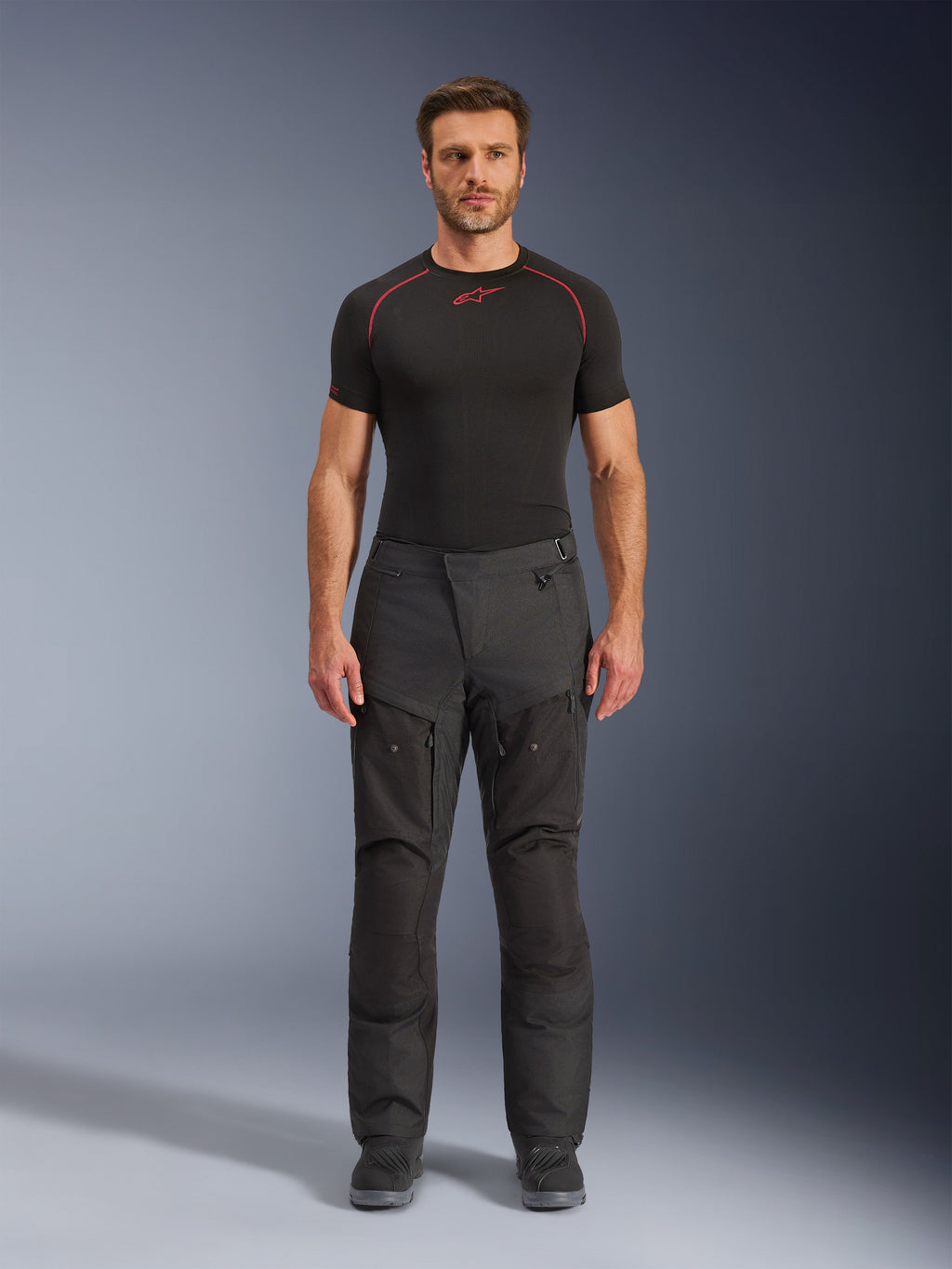 Alpinestars Cusco Drystar® Byxor, MC-byxor i textil, svarta, bärs av en modell med svart underställ och stövlar, adventure touring-design med ventilationspaneler med dragkedja på låren och slitstark konstruktion i flera paneler