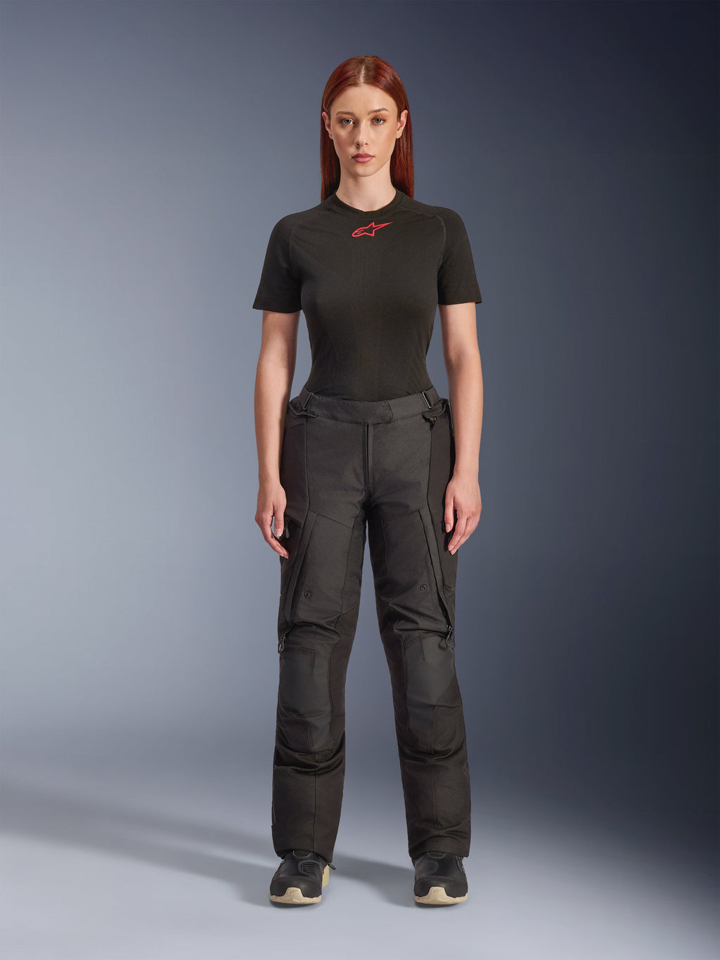 Alpinestars Stella Andes V4 Drystar®-byxor, svarta motorcykelbyxor för damer för äventyr och touring, visas på en modell med en svart Alpinestars t-shirt, teknisk textildesign med cargofickor och förstärkta knäpaneler.