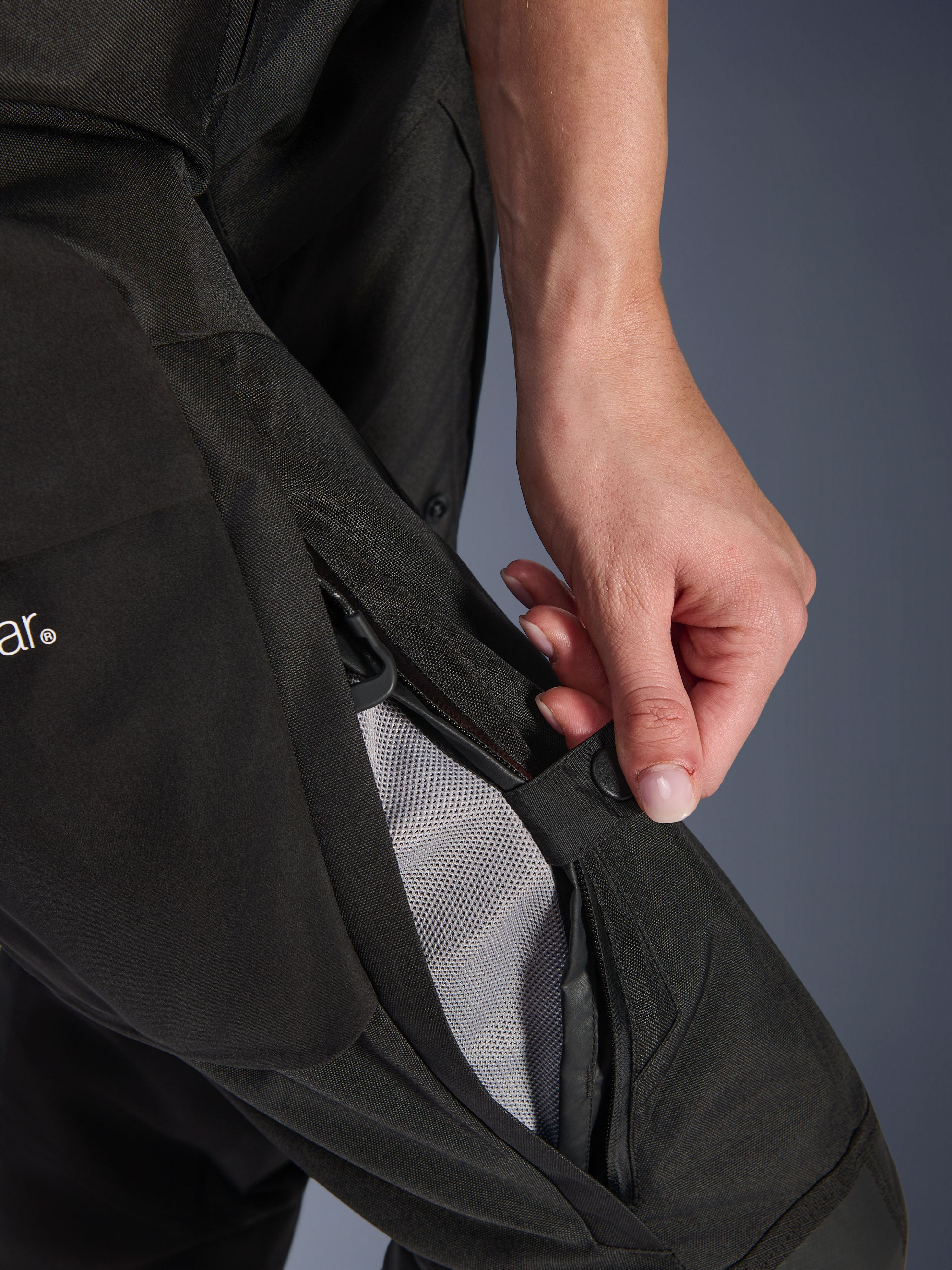 Alpinestars Stella Andes V4 Drystar®-byxor för dam, motorcykelbyxor, svarta, närbild på en hand som öppnar lårventilationen med dragkedja för att visa meshfoder för luftflöde, slitstark textil äventyrsutrustning
