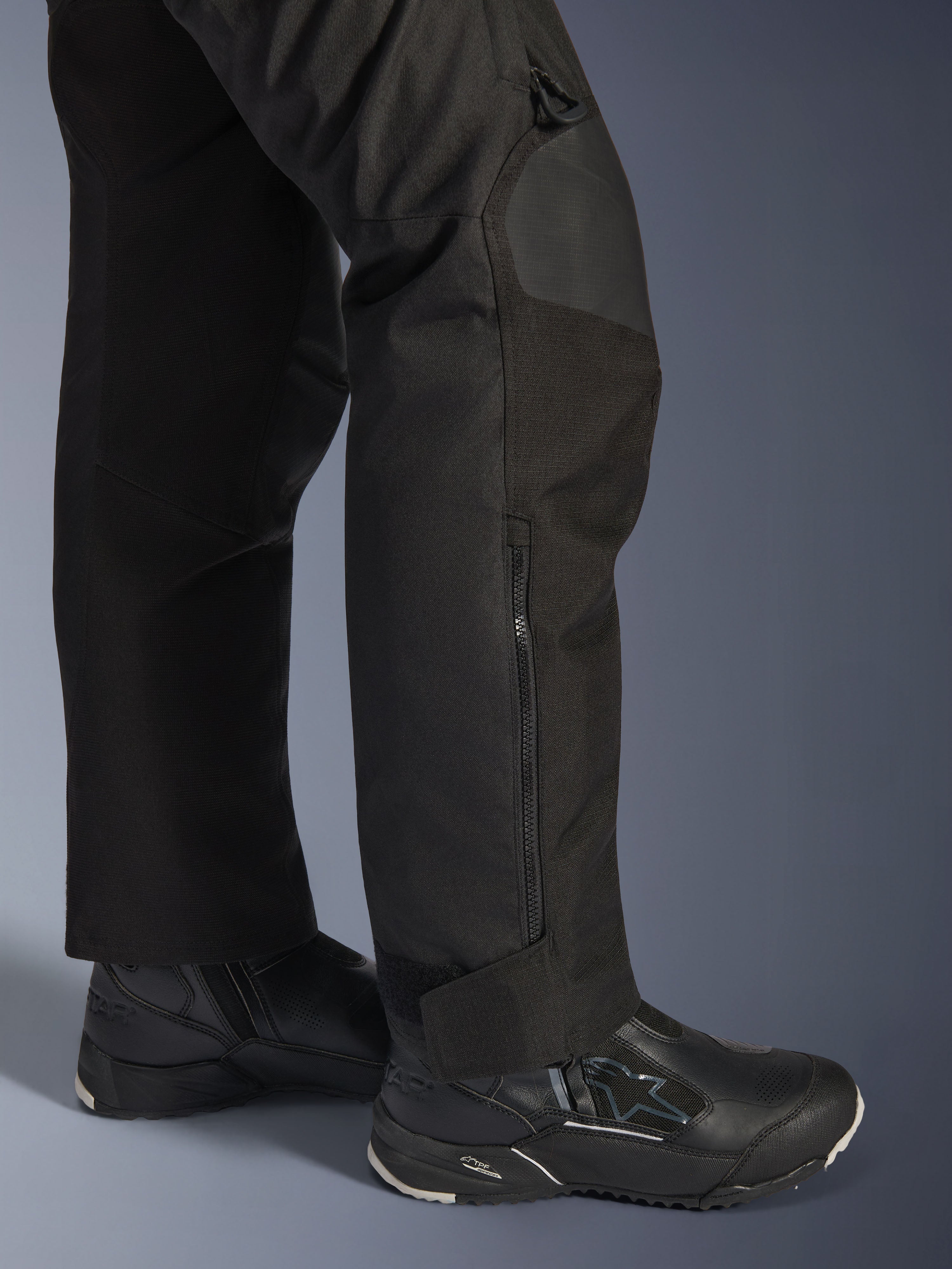 Alpinestars Stella Andes V4 Drystar® byxor, motorcykelbyxor för dam, svarta, närbild på underbenet med sidodragkedja och justerbart benslut, bärs med svarta Alpinestars MC-stövlar