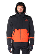 Alpinestars Mootant Waterproof Parka, Motorcycle Jacket, Spicy Orange and Black, modular all-weather design with hood, front zippered pockets, and orange strap details on sleeves, worn by a model with black gloves and pants