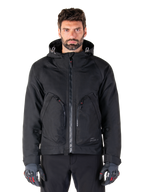 Alpinestars Morush Waterproof Parka, Black Motorcycle Jacket, Hooded Design with Front Zipper and Two Large Zippered Pockets, Worn with Black and Red Gloves, Urban Riding Gear