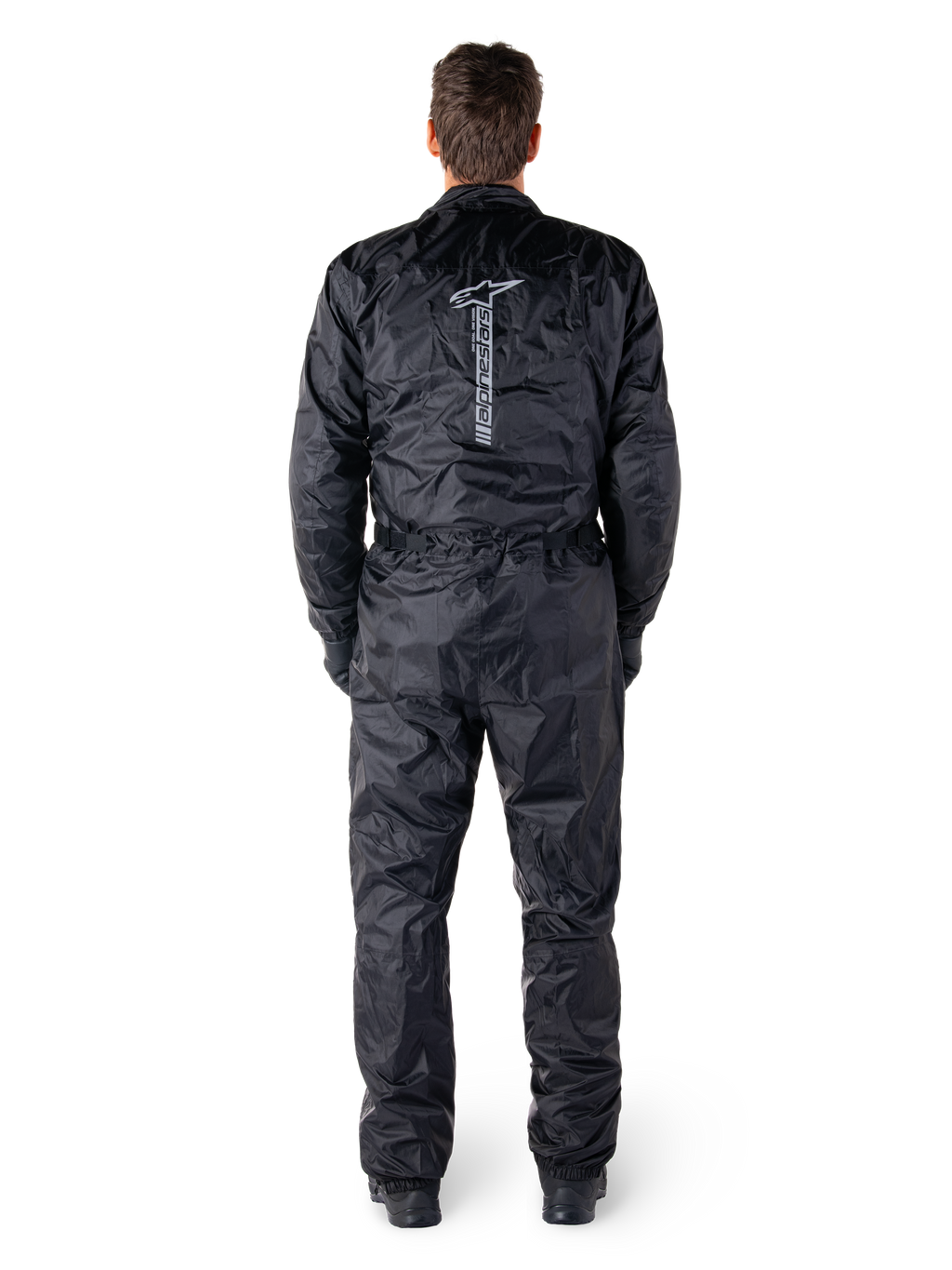 Alpinestars Hurricane Rain V2 Suit, svart vattentät motorcykeloverall, vy bakifrån som visar stort vertikalt Alpinestars-ordmärke och logotyp, lätt skrynkligt material med elastisk midja och muddar, designad för skydd vid körning i vått väder