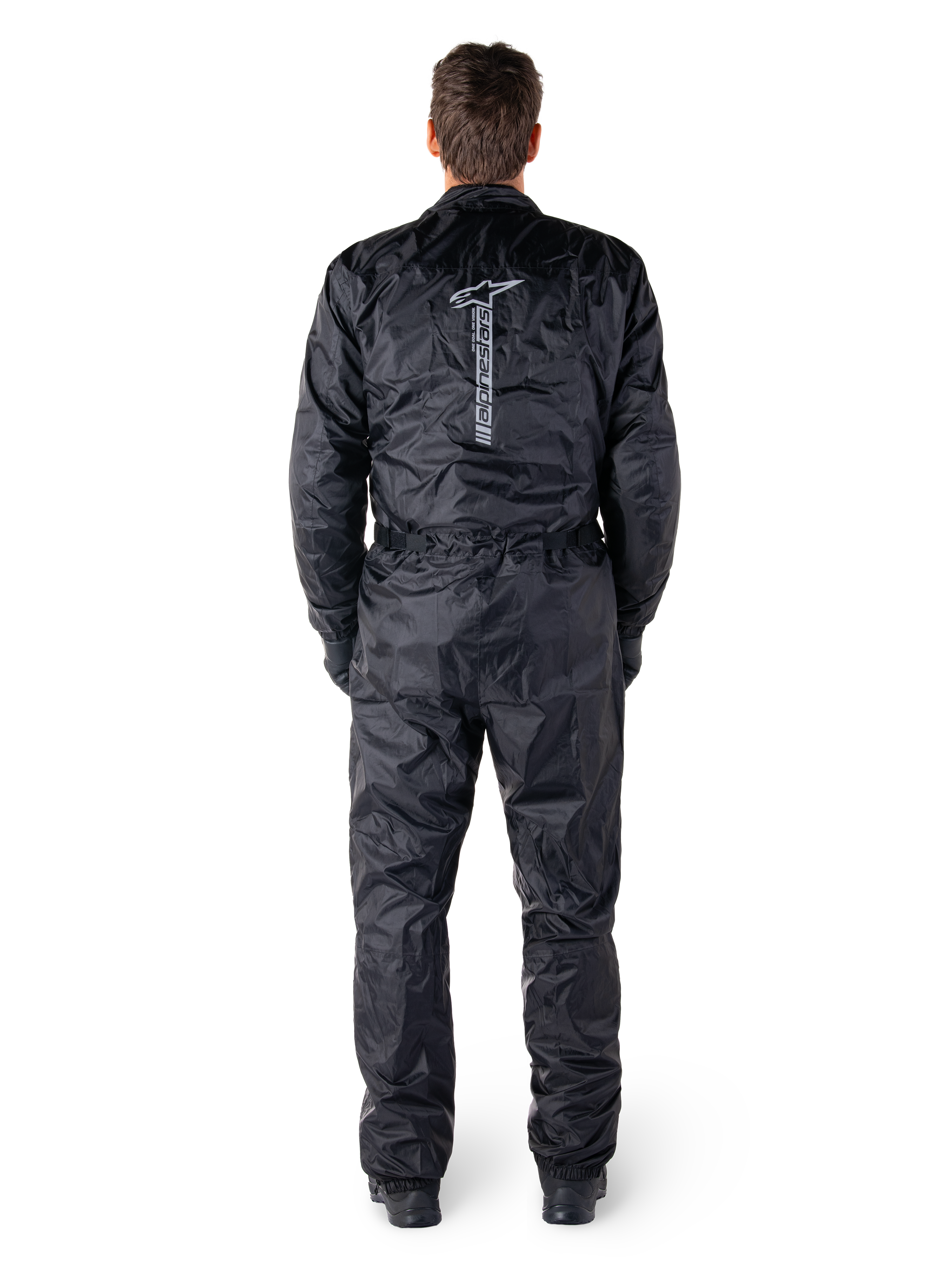 Alpinestars Hurricane Rain V2 Suit, svart vattentät motorcykeloverall, vy bakifrån som visar stort vertikalt Alpinestars-ordmärke och logotyp, lätt skrynkligt material med elastisk midja och muddar, designad för skydd vid körning i vått väder