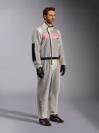 Alpinestars Kart Rain Suit, genomskinlig vattentät regndräkt för karting, halvgenomskinligt material som visar en rosa och vit racingoverall under, med en svart asymmetrisk dragkedja, förstärkt armbågsparti och svart midjeband, bärs med svarta kartinghandskar och racingskor.