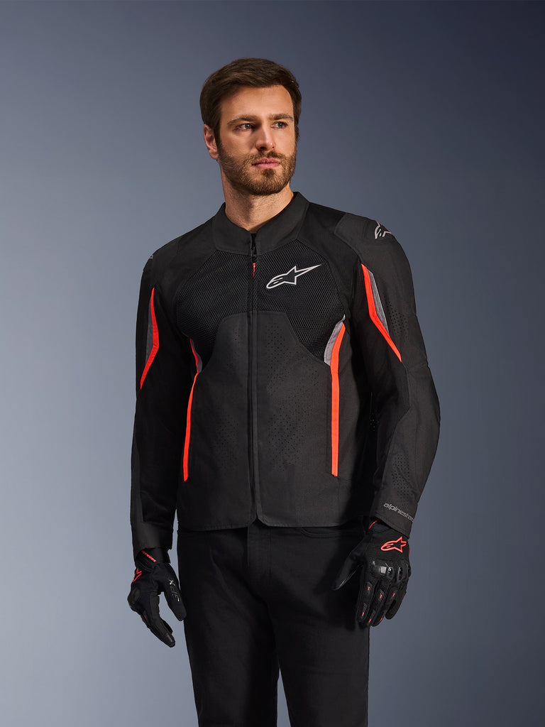 Alpinestars AST V3 Air-jacka, svart, mörkgrå och röd fluo, bärs av en man med matchande handskar och svarta byxor, utrustad med tekniska mesh-paneler, laserperforerade bröstpartier och livfulla röda detaljer, sportmotorcykelkläder för prestanda