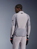 Alpinestars Aeroshell Airflow-jacka i Mid Gray Anthracite, ryggvy som visar ventilerande meshpaneler och laserperforeringar, teknisk stretch-softshellkonstruktion med en förlängd bakpanel, bärs med matchande gråa byxor och svarta handskar för en sportig look.