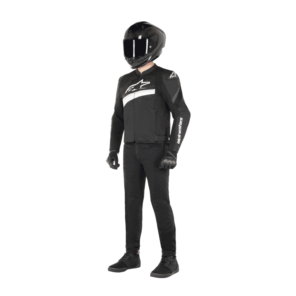 Förare iförd Alpinestars T-GP Plus R V4 Airflow-jacka i svart och vitt, textiljacka för motorcykel med meshpaneler och vita Alpinestars-logotyper, kombinerad med en svart hjälm, svarta mc-handskar, svarta byxor och svarta skor