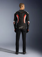 Alpinestars T-GP Air-jacka, motorcykeljacka, Black Red Fluo, sedd bakifrån på en modell, med en aerodynamisk puckel, vita och fluorescerande röda detaljer, Alpinestars-logotyp på ländryggen, sportig design för landsvägskörning.