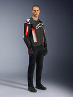Alpinestars T-GP Air-jacka, Black Red Fluo, bärs av modell med svarta körbyxor och handskar, med laserperforerade textilpaneler, vit Alpinestars-logotyp och röda detaljer, sportig motorcykeljacka för körning på väg i varmt väder