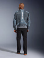 Alpinestars Flight Air-jacka i Storm Gray, baksidesvy av manlig modell i en motorcykeljacka i urban stil med 3D-meshpaneler och vertikal Alpinestars-logotyp, matchad med svarta byxor för en modern pendlarlook
