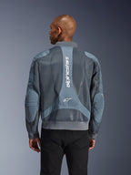 Alpinestars Flight Air-jacka i Storm Gray, baksida på en modell, urban motorcykeljacka med utökade 3D-meshpaneler, vertikal Alpinestars-märkning på ryggen samt ribbad fåll och krage i bomberstil.