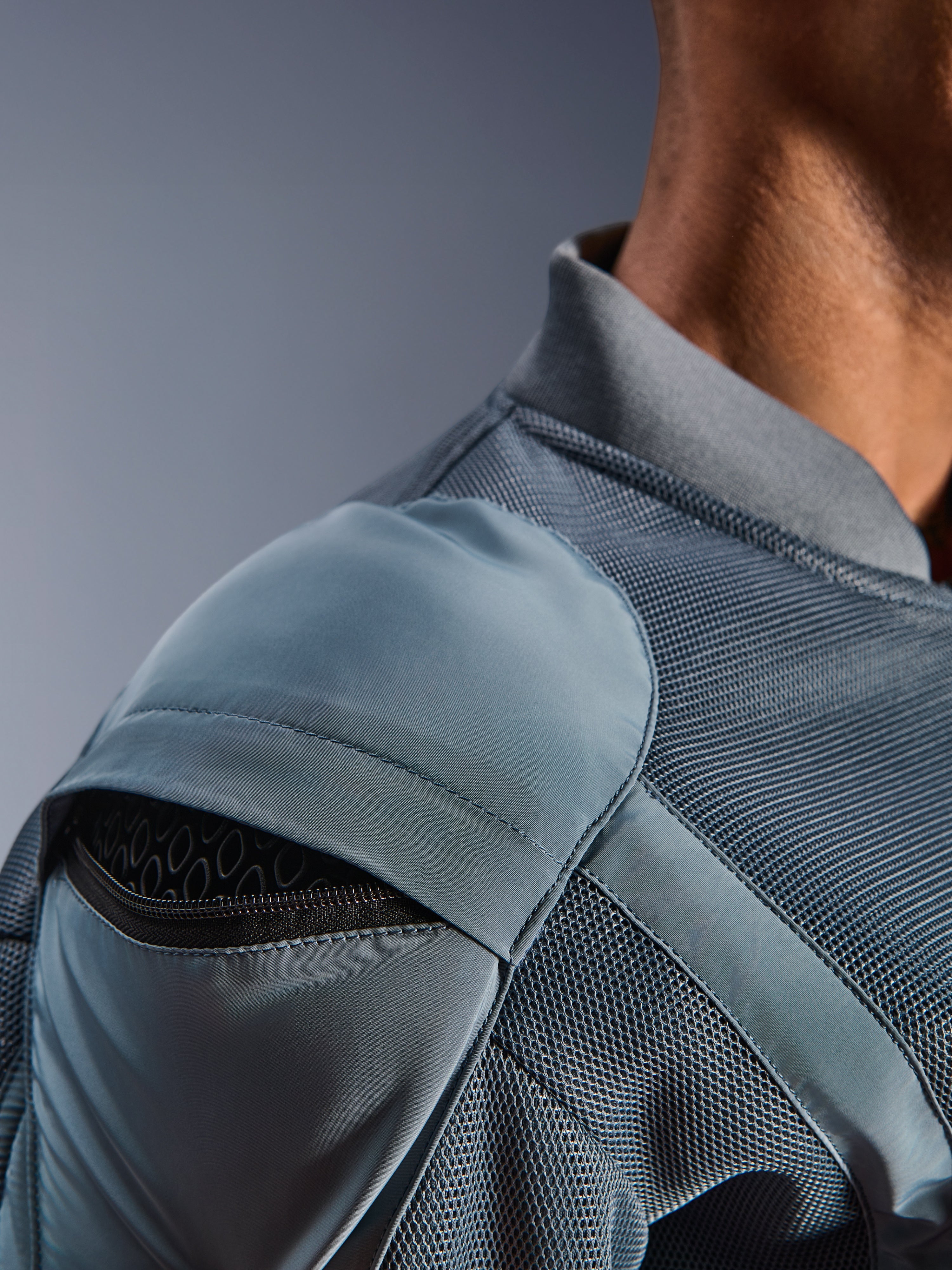 Närbild på Alpinestars Flight Air Jacket i Storm Gray, som visar den yttre axelskyddsfickan med synligt bikakeformat skydd, 3D-meshpaneler och ribbad krage för teknisk urban motorcykelkörning.