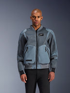 Alpinestars Flight Air-jacka, urban mc-jacka i bombermodell, Storm Gray, med ventilationspaneler i 3D-mesh och vit Astars-logotyp, bärs av manlig modell med svarta byxor, modern urban körutrustning
