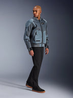 Alpinestars Flight Air-jacka, Storm Gray, urban bomber-inspirerad motorcykeljacka, bärs av en manlig modell med svarta byxor och sneakers, utrustad med utökade ventilationspaneler i 3D-mesh och externa skyddsfickor, modern streetwear-skyddsutrustning för körning i varmt väder