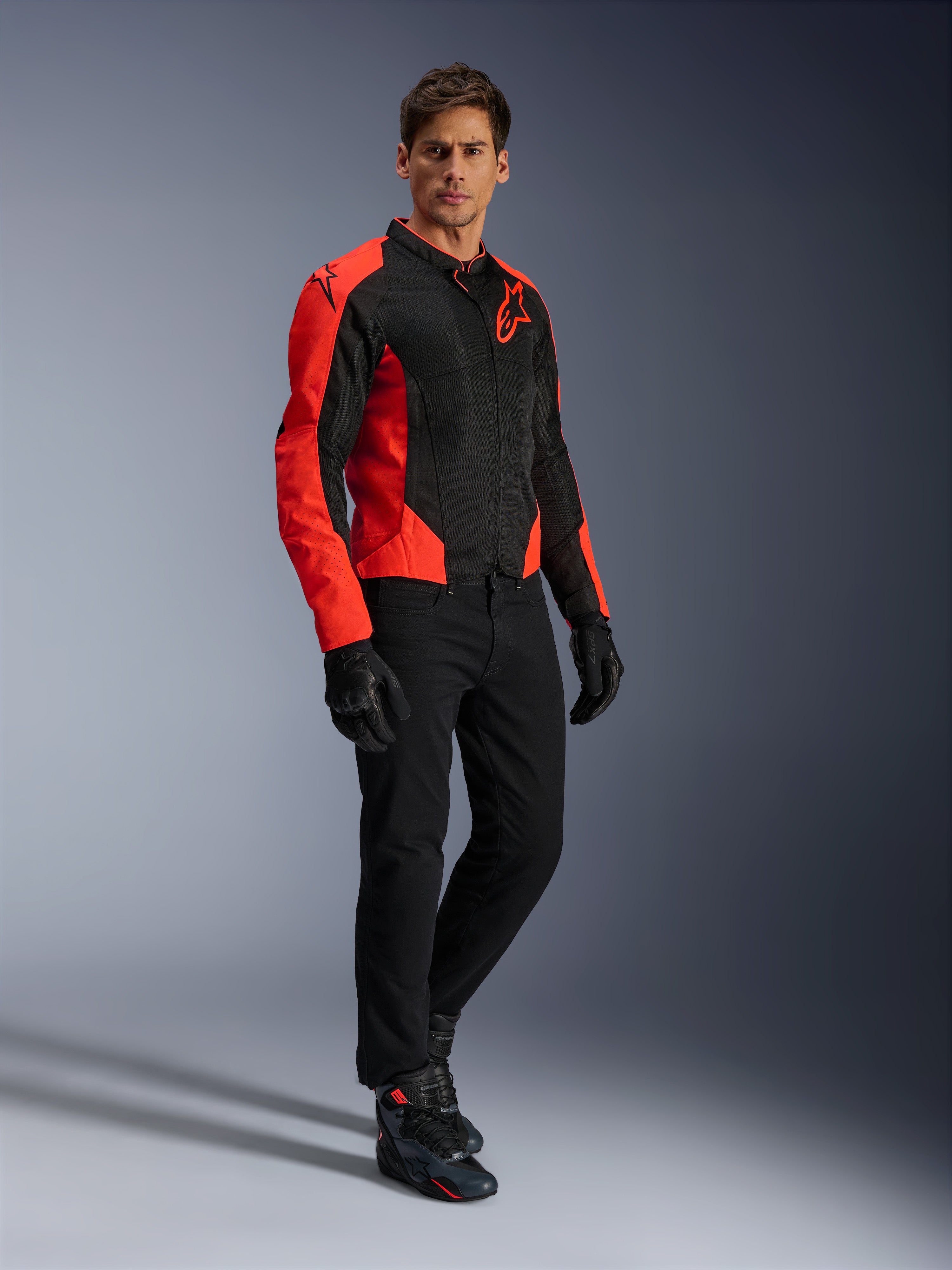 Alpinestars Viper Air V4-jacka, motorcykeljacka, röd fluo och svart, bärs av modell med svarta MC-jeans, svarta handskar och motorcykelskor, textil mesh-design med markerade röda paneler och stjärnlogotyp, sportig vägkörningsutrustning