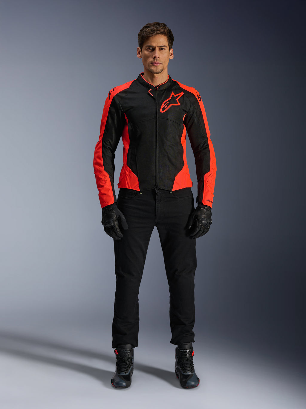 Manlig modell som bär Alpinestars Viper Air V4-jacka i Red Fluo och svart, kombinerad med svarta körbyxor, handskar och stövlar, med meshpaneler som andas för ventilation och en tydlig stjärnlogotyp på bröstet, sportig motorcykelutrustning för vägkörning