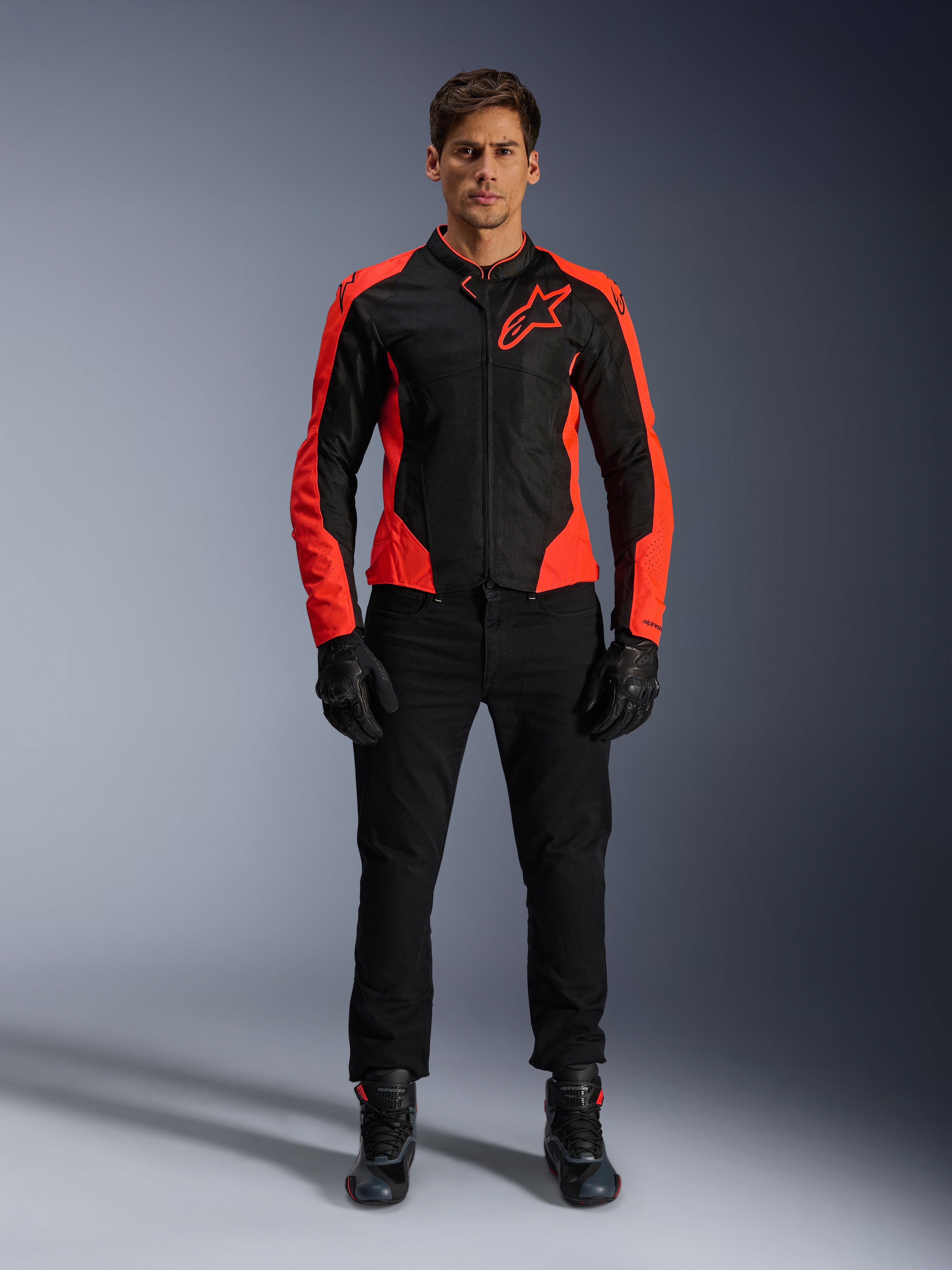 Manlig modell som bär Alpinestars Viper Air V4-jacka i Red Fluo och svart, kombinerad med svarta körbyxor, handskar och stövlar, med meshpaneler som andas för ventilation och en tydlig stjärnlogotyp på bröstet, sportig motorcykelutrustning för vägkörning