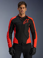 Alpinestars Viper Air V4-jacka, motorcykeljacka för racing, röd fluo och svart, bärs av modell med svarta handskar, tekniska mesh-paneler för ventilation, sportig design med Alpinestars stjärnlogotyp på bröstet