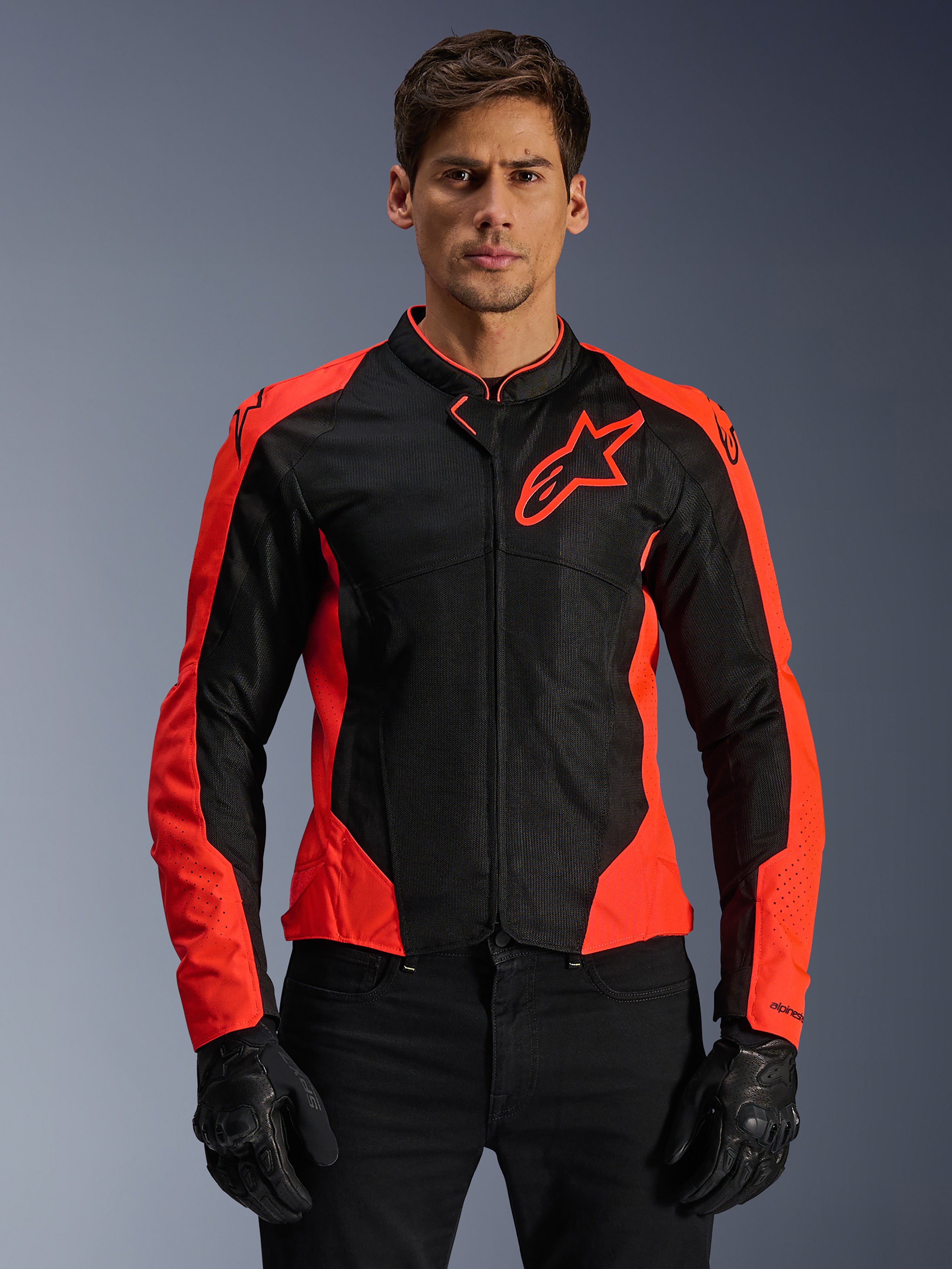 Alpinestars Viper Air V4-jacka, motorcykeljacka för racing, röd fluo och svart, bärs av modell med svarta handskar, tekniska mesh-paneler för ventilation, sportig design med Alpinestars stjärnlogotyp på bröstet