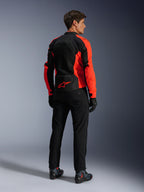 Alpinestars Viper Air V4-jacka, röd fluo svart, sedd bakifrån på modell, med tekniska meshpaneler och en röd stjärnlogotyp på nedre ryggen, kombinerad med svarta motorcykelbyxor och handskar för en komplett look för vägkörning.