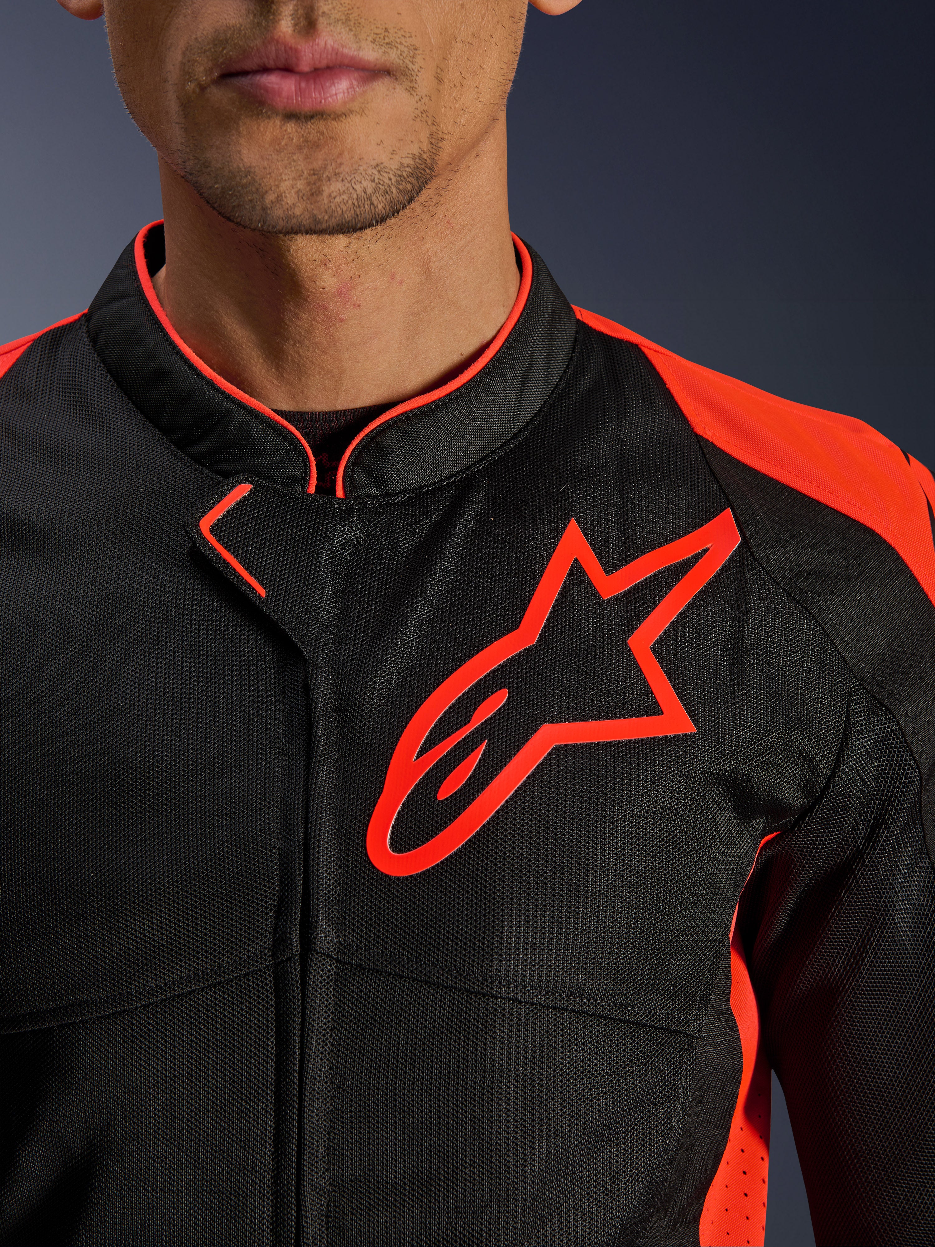 Alpinestars Viper Air V4-jacka i Red Fluo Black, närbild på bröstet och kragen, med svart konstruktion i teknisk mesh, en framträdande röd Alpinestars-logotyp och livfulla röda detaljer på axlarna.