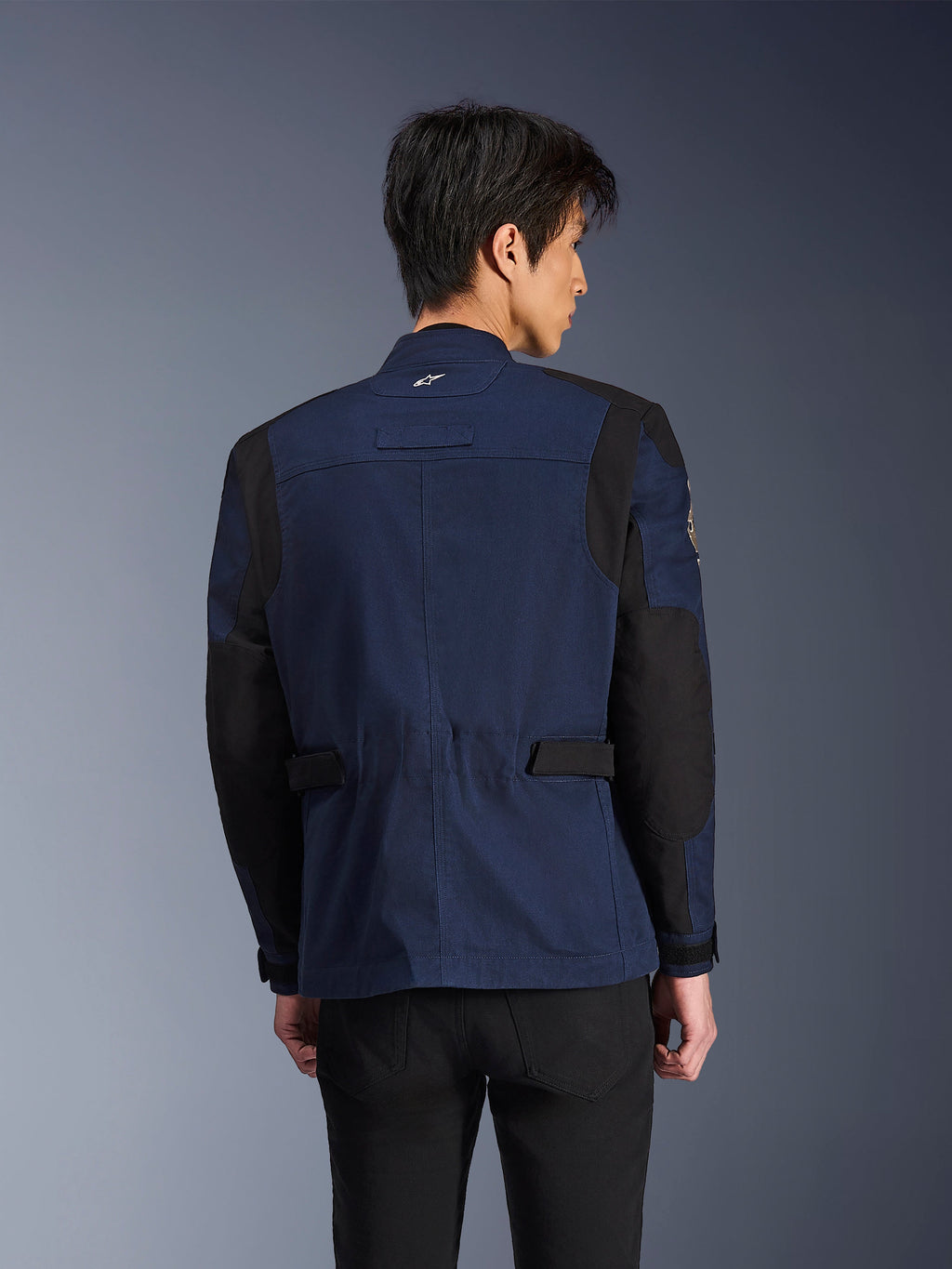 Alpinestars Dice Jacket, Dark Blue and Black urban field motorcycle jacket, back view worn by a man, featuring reinforced black shoulder and elbow panels with adjustable waist tabs.