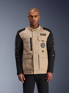 Alpinestars Dice Jacket, urban motorcykeljacka, beige och svart, robust arbetsklädesestetik med flera praktiska fickor och bröstmärken, hög krage med knappstängning, tydlig logotyp på ärmarna, bärs av en manlig modell